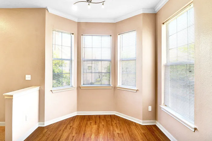 Bright and inviting corner space with large sunlit windows and elegant wood flooring.