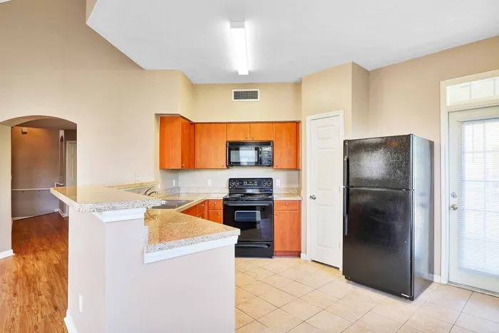 Modern kitchen with sleek black appliances, warm wooden cabinets, and elegant granite countertops, perfect for culinary creativity.