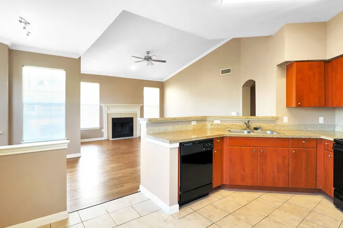 Modern open-concept living area with a sleek kitchen, granite countertops, hardwood floors, and a cozy fireplace.