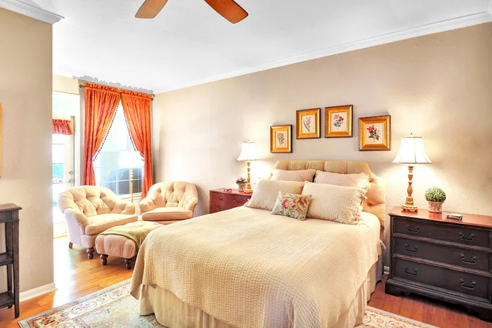 Cozy and elegantly decorated bedroom featuring a plush bed, stylish armchairs by the window, and warm lighting exuding a welcoming atmosphere.