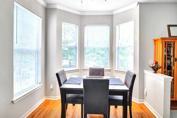 Bright, inviting dining area with large windows, modern furniture, and elegant wood flooring.
