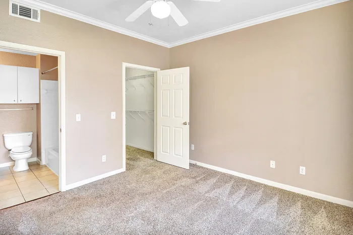 Bright bedroom with plush carpet, attached bathroom, and spacious walk-in closet, offering a fresh canvas for personalization.