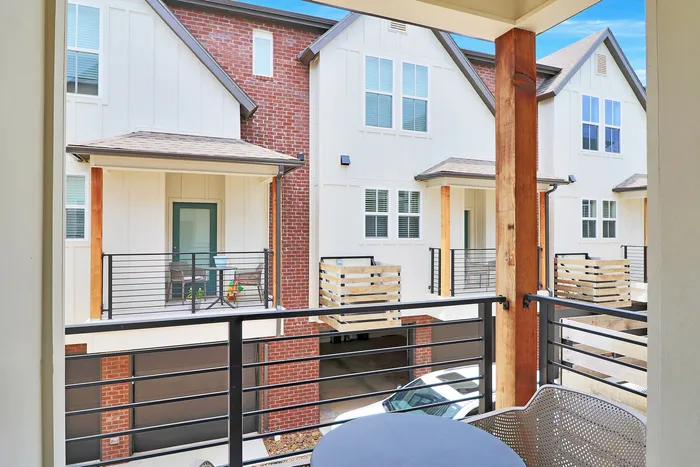 Charming balcony view overlooking modern townhomes with stylish brick and siding exteriors, showcasing inviting outdoor seating areas.