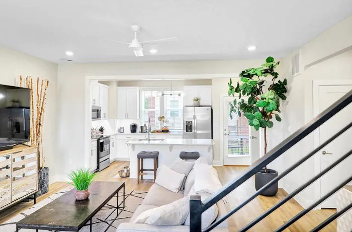 Modern open-concept living room and kitchen with sleek white cabinetry, spacious island, and stylish decor, perfect for contemporary living.