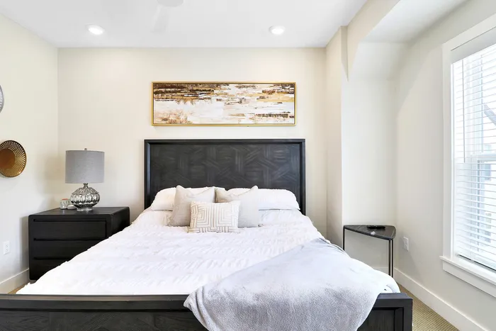 Bright and inviting bedroom with a stylish modern bed, cozy white bedding, chic nightstands, and elegant wall art.