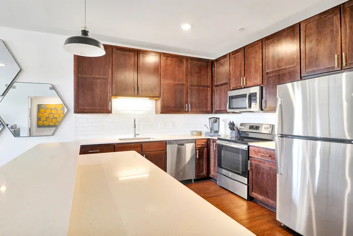 Modern kitchen featuring sleek stainless steel appliances, elegant dark wood cabinetry, and a stylish pendant light over a spacious island counter.