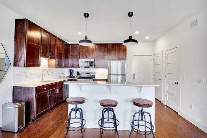 Modern kitchen with rich wooden cabinets, sleek stainless steel appliances, and elegant bar seating.