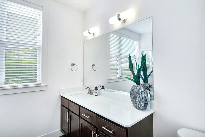 Modern bathroom vanity featuring a sleek countertop, elegant lighting, and stylish decor in a bright, spacious setting.