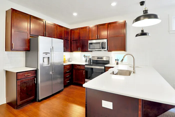 Modern kitchen with rich wooden cabinets, sleek stainless steel appliances, and elegant pendant lighting creating a warm, inviting space.