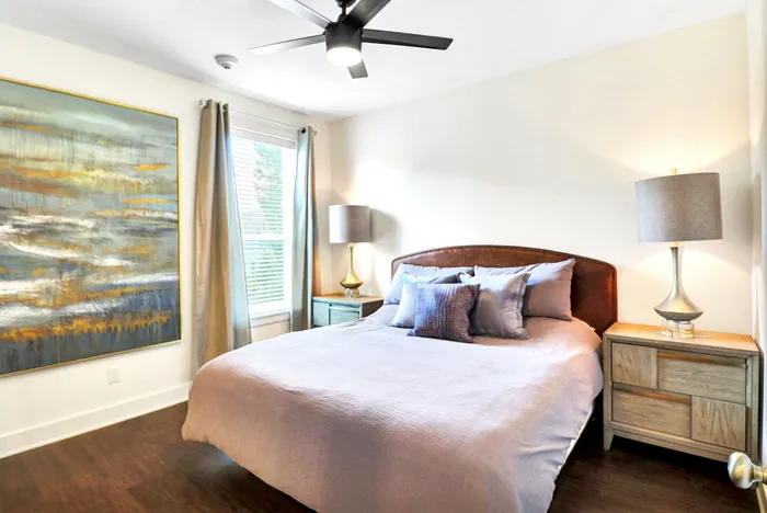 Inviting bedroom with plush bedding, elegant artwork, and warm lighting, perfect for a cozy retreat.