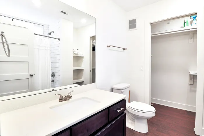 Bright, modern bathroom with sleek vanity, elegant fixtures, and ample shelving space for storage.