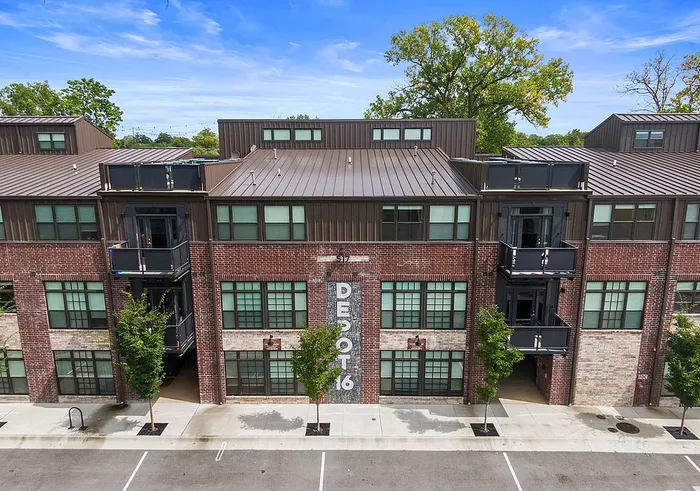 Charming urban apartment building with red brick facade, large windows, and spacious balconies, perfect for modern living.