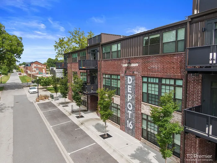 Chic urban apartment complex with contemporary brick facade, large windows, and private balconies, nestled in a vibrant neighborhood with scenic views and tree-lined streets.