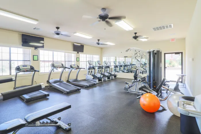 Bright and modern fitness center with state-of-the-art treadmills, exercise machines, and large windows for natural light.