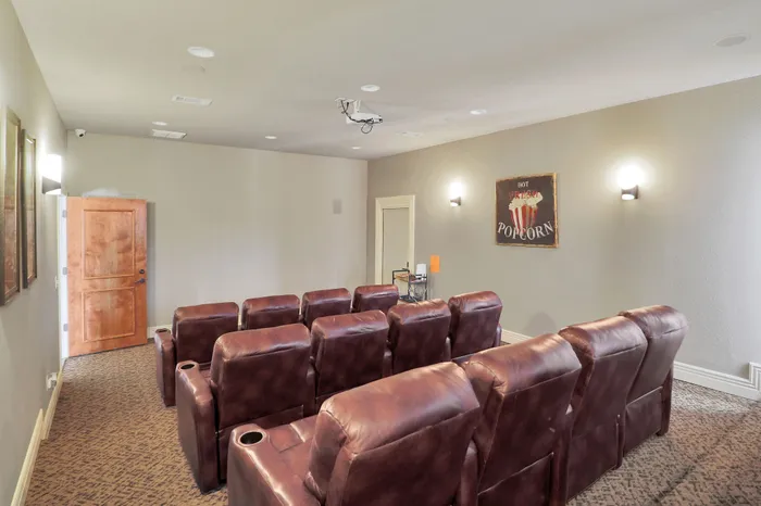 Cozy home theater room featuring plush leather recliners and ambient wall lighting for ultimate relaxation.