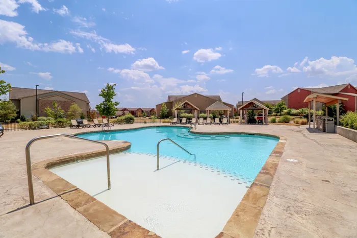 Inviting outdoor pool area with sun loungers and cabanas, perfect for relaxation and entertaining in a scenic community setting.