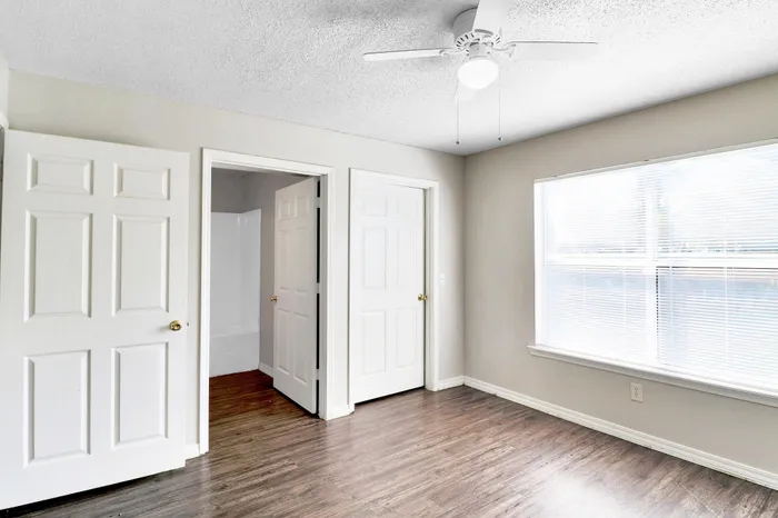Bright and spacious bedroom with elegant hardwood flooring and large windows, perfect for natural light.