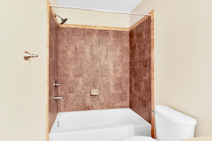 Elegant bathroom featuring a stylish tiled bathtub, modern shower, and pristine white fixtures.