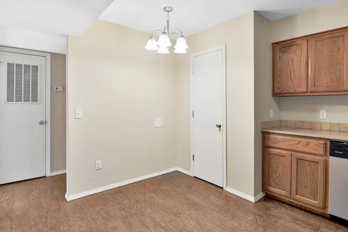 Charming apartment interior featuring warm wood cabinetry, elegant lighting, and beautiful wood flooring, perfect for cozy living.