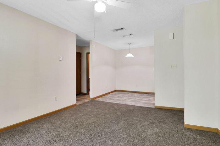 Bright and inviting open-concept living area with new carpeting and modern ceiling light fixtures.