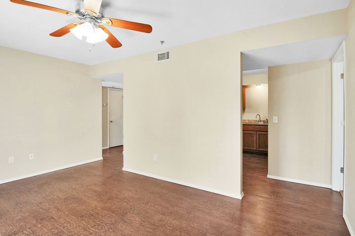 Bright and inviting living space with elegant hardwood floors, classic ceiling fan, and open access to a cozy kitchenette.