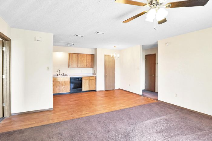 Inviting open-plan apartment with warm wood flooring, cozy kitchen cabinets, and elegant ceiling fan lighting.