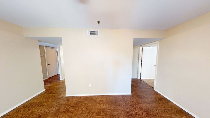 Inviting apartment with warm wooden floors, neutral walls, and ample natural light for a cozy ambiance.