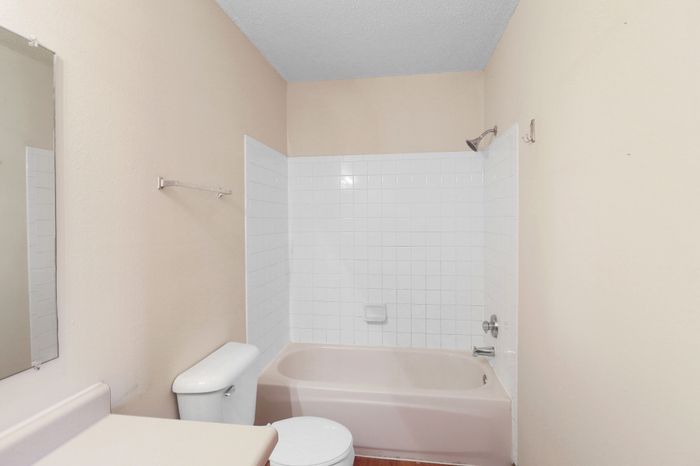 Bright and airy bathroom with a clean white tiled bathtub, elegant fixtures, and neutral tones perfect for relaxation.