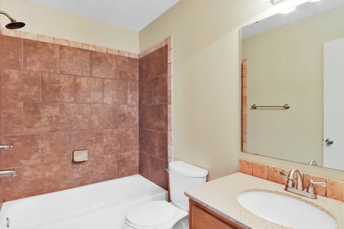Modern bathroom with elegant tiled walls, a pristine bathtub, and sleek fixtures, offering a serene and refreshing retreat.