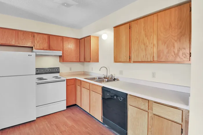 Inviting kitchen with warm wooden cabinets, modern white appliances, and sleek countertops.
