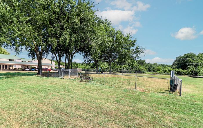 Expansive community green space with vibrant trees and a fenced area, providing a serene and inviting outdoor setting.