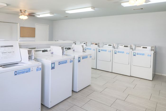 Bright and spacious communal laundry room featuring modern washers and dryers on sleek tiled flooring.