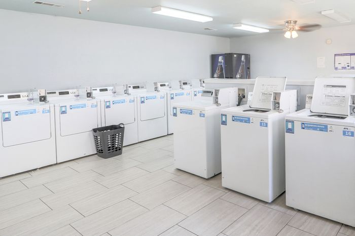 Modern laundry room with multiple washing machines, bright lighting, and a sleek tiled floor, ensuring a convenient and efficient laundry experience.