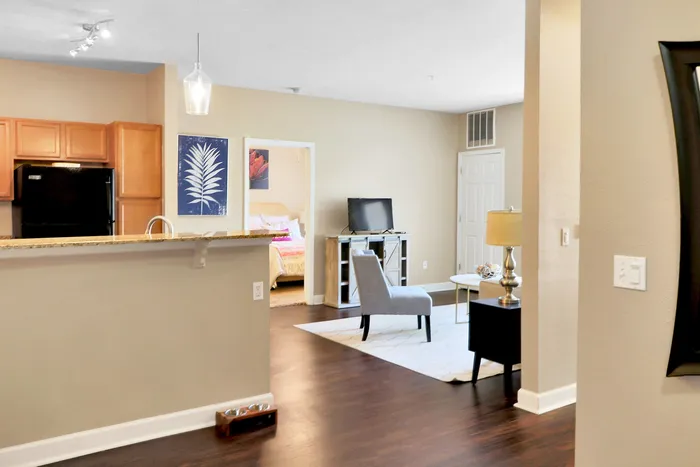 Modern apartment interior featuring an open-concept living area with elegant wooden flooring, stylish kitchen with granite countertops, and cozy bedroom entrance.