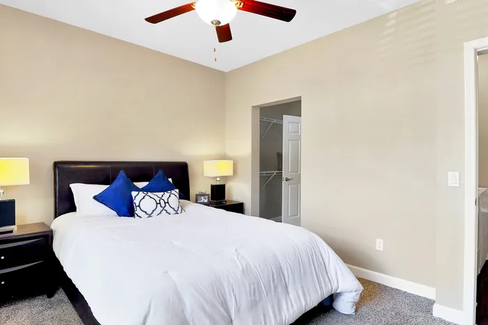 Inviting bedroom with cozy white bedding, modern dark wood furniture, and soft lighting, enhancing a relaxing atmosphere.