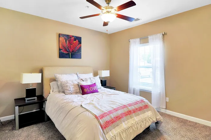 Inviting bedroom with a plush bed, elegant decor, and natural light from a large window.