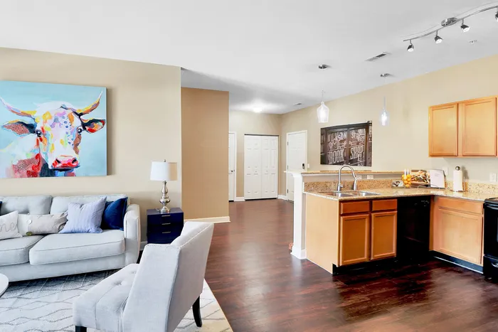 Bright, open-concept living area featuring vibrant artwork, modern kitchen with granite countertops, and cozy seating.