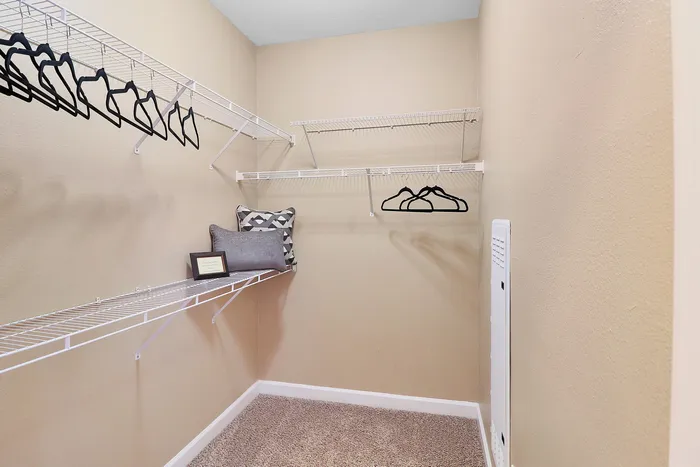 Spacious walk-in closet with elegant shelving, plush carpet, and cozy storage nook.
