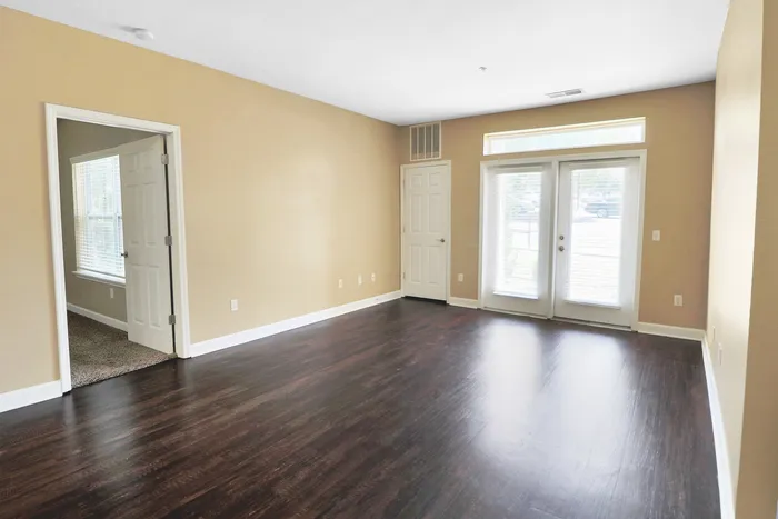 Inviting living area with elegant dark hardwood floors, abundant natural light from large windows, and cozy adjacent room.