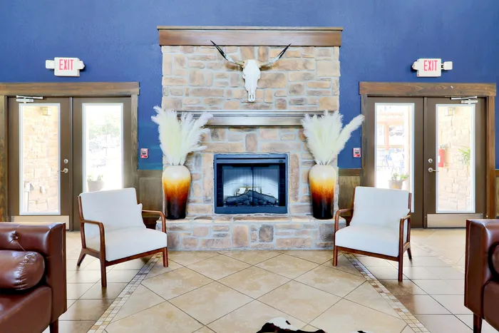 Inviting living room with a stone fireplace, elegant armchairs, and rustic decor for a cozy ambiance.