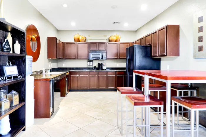 Modern kitchen with rich wooden cabinets, sleek black appliances, and a stylish bar table with matching stools, offering a chic and functional culinary space.