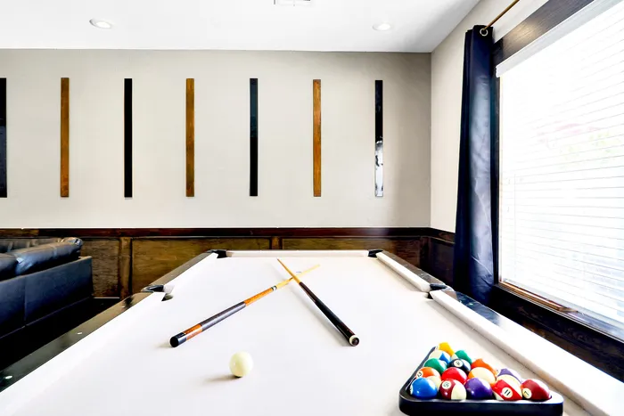 Chic apartment recreational space featuring a pristine pool table by a sunlit window, perfect for entertaining.