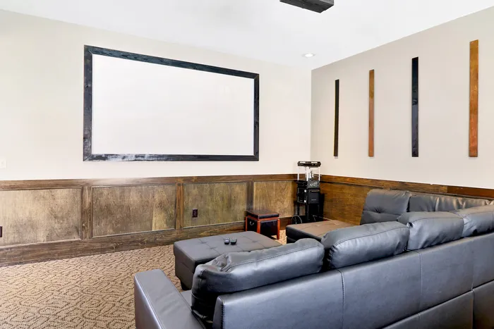 Elegant home theater room with plush leather seating and a large projection screen, perfect for entertainment.