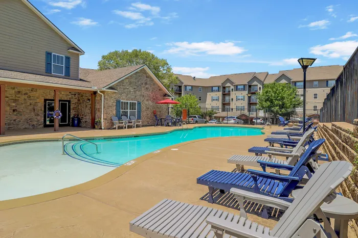Inviting outdoor pool area with comfortable lounge chairs, surrounded by charming residences and lush greenery.