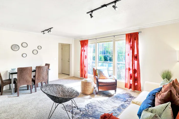 Bright and inviting living room with cozy seating, vibrant red curtains, and an abundance of natural light.