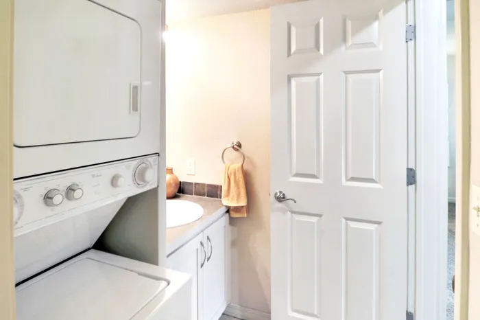 Charming apartment bathroom featuring a convenient in-unit washer and dryer with sleek cabinetry.