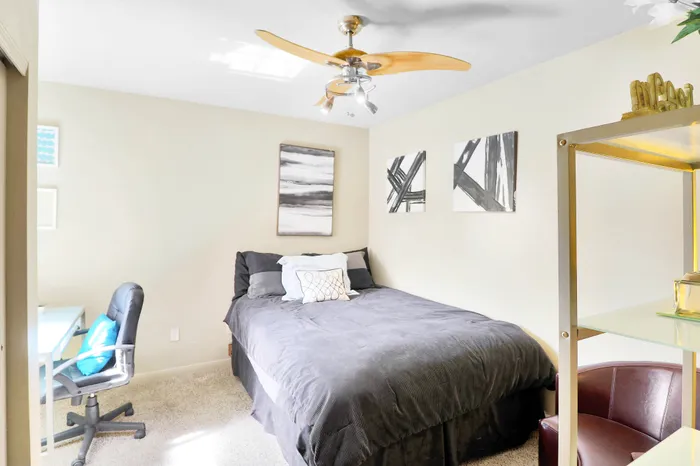 Bright, modern bedroom with plush bed, sleek ceiling fan, and elegant decor, ideal for comfort and style.