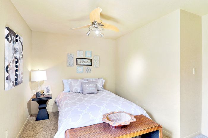 Cozy bedroom with elegant modern decor, featuring a comfortable bed, stylish artwork, and a sleek ceiling fan.