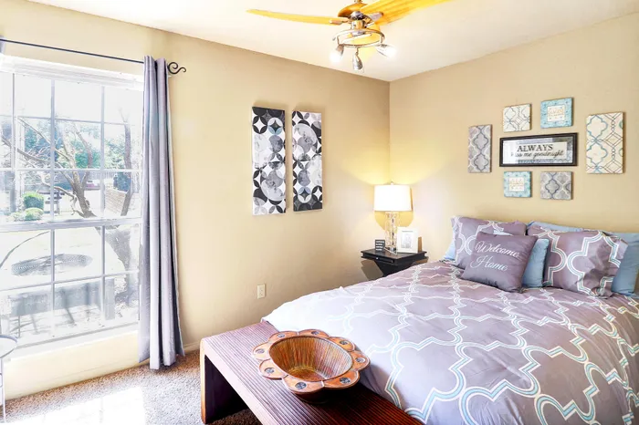 Bright and cozy bedroom with stylish decor, plush bedding, and a large window letting in natural light.