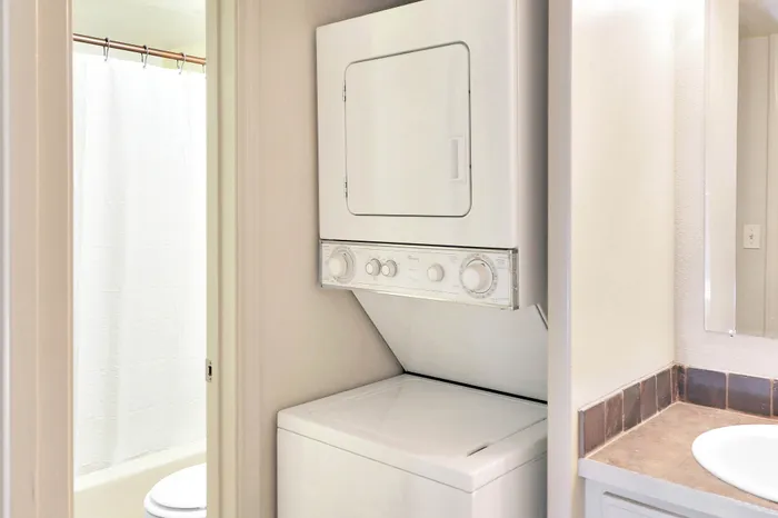 Convenient in-unit laundry with sleek stackable washer and dryer beside modern bathroom.